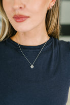Sterling silver necklace with a flower-shaped pendant and center stone, worn on a person.