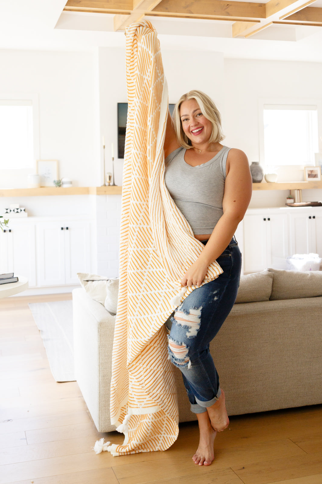 Yellow and white striped blanket with geometric design and tassels on all four corners.