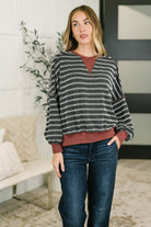 A woman wearing a black and white ribbed knit pullover with contrast details and a relaxed fit.
