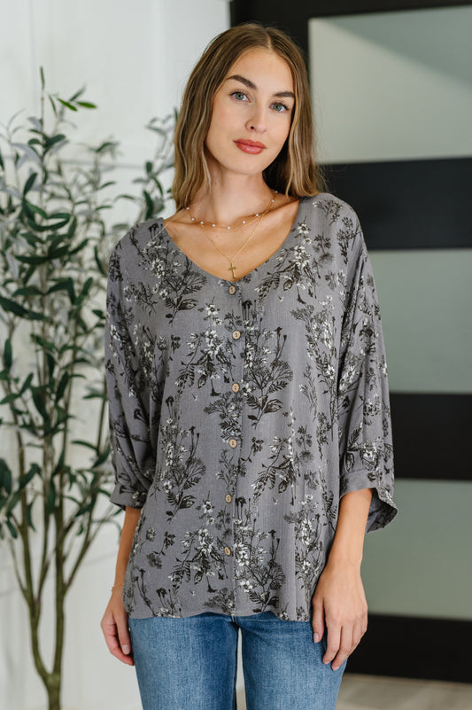 Woman wearing a gray floral blouse with a blurred background