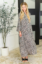 A woman wearing a leopard print maxi dress with a v-neckline and bell sleeves.