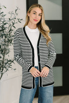 A woman wearing a black and white striped cardigan with button closures and a V-neckline.