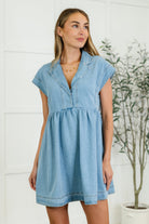 Woman wearing a mid-weight denim dress with a classic collared V-neckline and snap button closure.