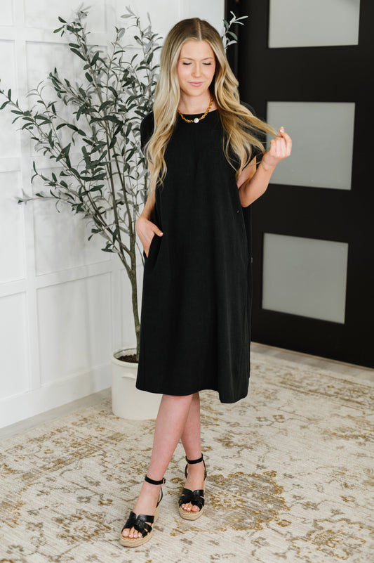 Woman wearing a black dress standing in a room with decorative elements.