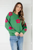 Green sweater with pink tufted flowers and balloon sleeves, worn by a model.