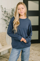 Model wearing a navy long sleeve top with drop shoulders and banded cuffs.