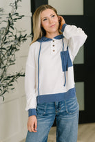 Woman wearing a blue and white color block hoodie with ribbed knit, long sleeves, and Henley button closures.