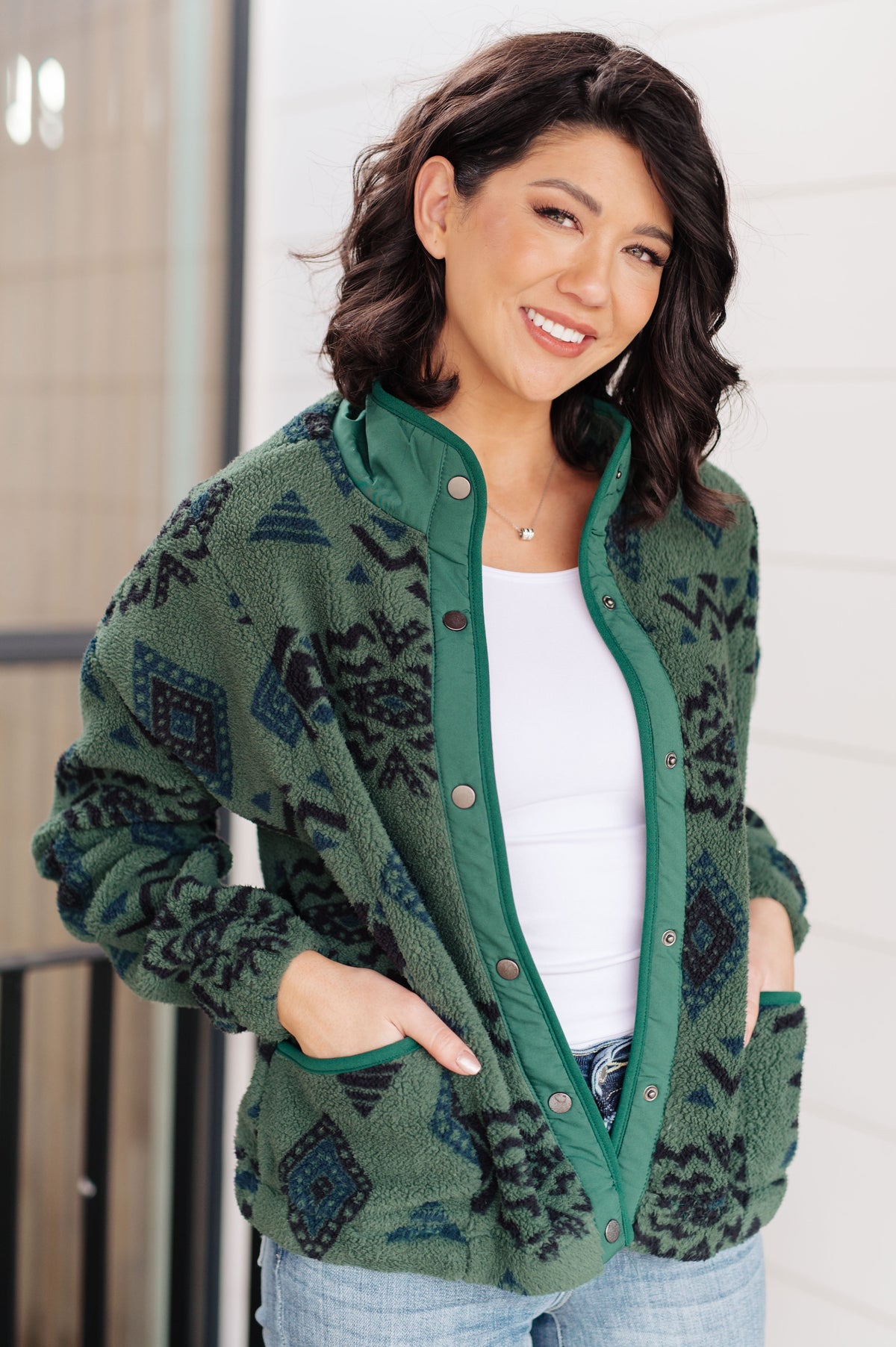 Woman wearing a green geometric pattern fleece jacket with a snap front and mock neckline.