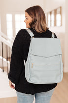 Blue baby bag with multiple pockets and adjustable straps worn as a backpack by a model.