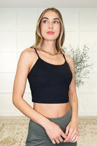 A woman wearing a black cropped tank top with adjustable straps, made from brushed microfiber fabric.