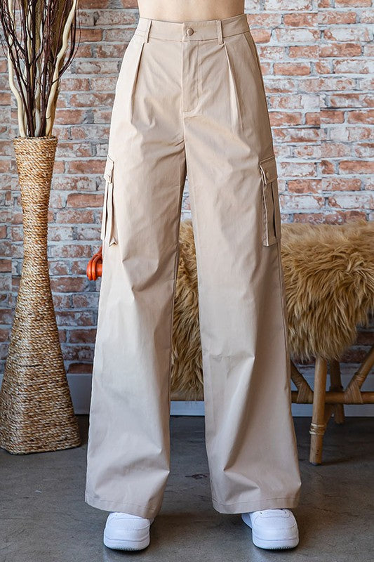 Woman wearing beige cargo pants standing in front of a brick wall.