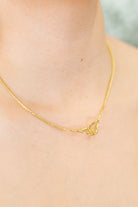 Gold necklace on a woman's neck against a neutral background