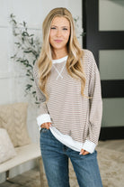 Woman wearing a striped drop shoulder pullover with contrast ribbed accents, paired with jeans.
