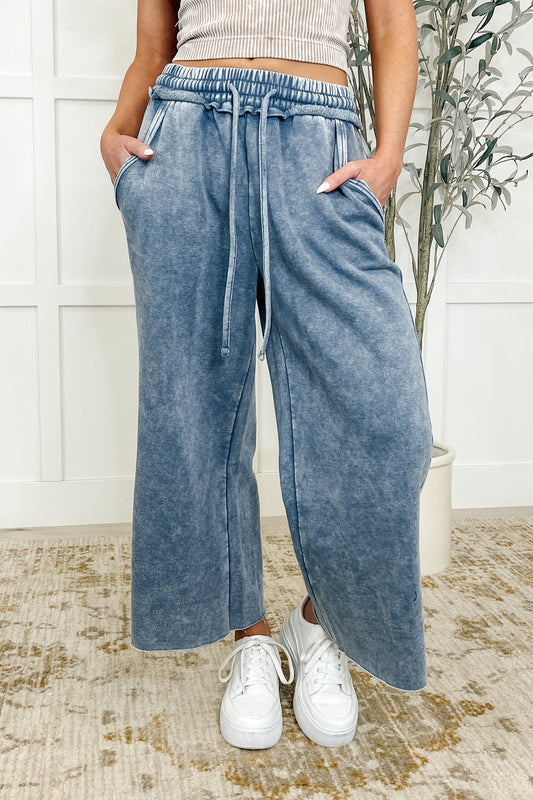 A woman wearing wide leg cropped pants with a drawstring waist and side pockets, in a blue grey color.