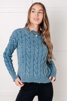 Model wearing a mineral washed cable knit sweater with distressed ribbed neckline and cuffs.