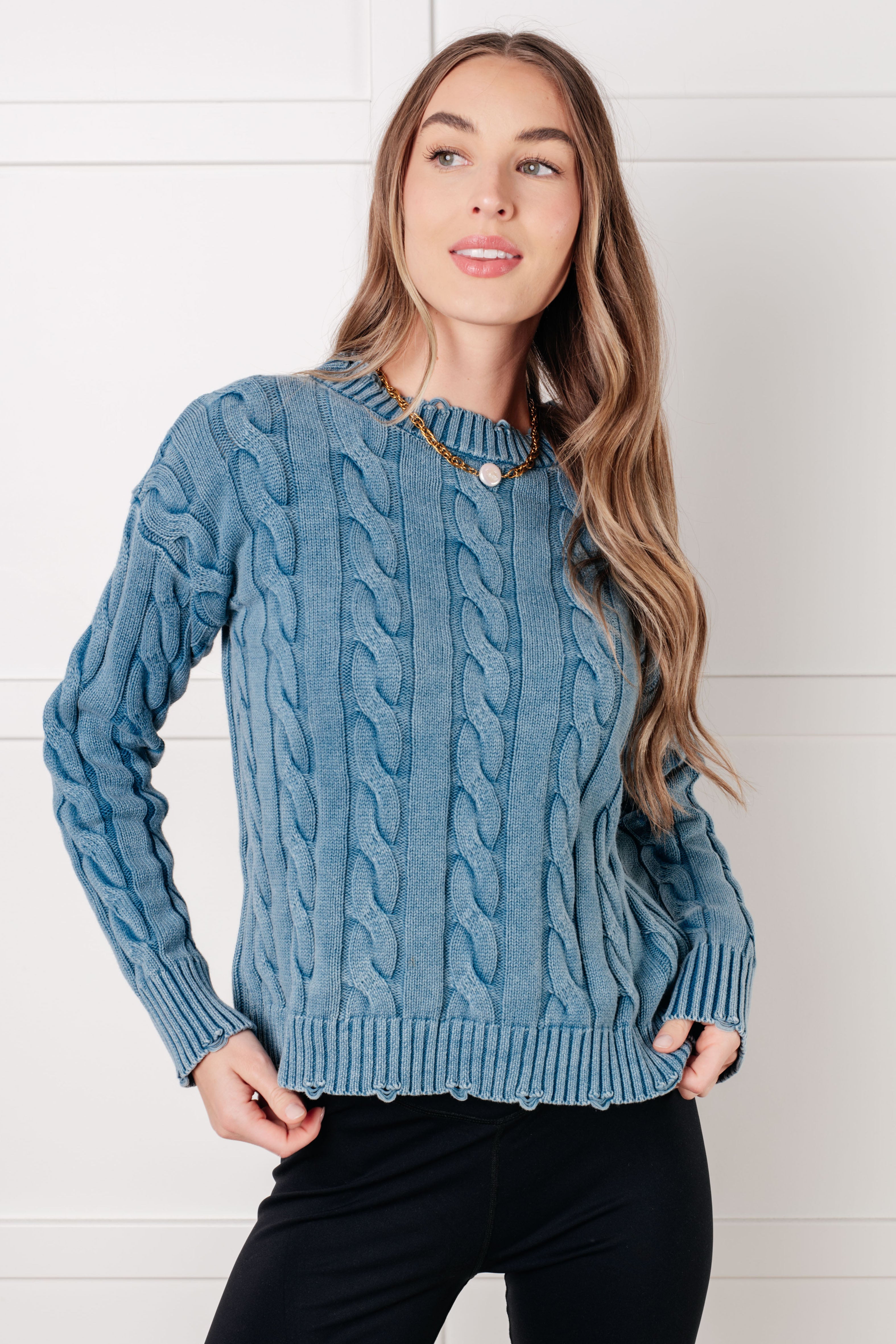 Model wearing a mineral washed cable knit sweater with distressed ribbed neckline and cuffs.