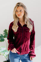 A wine-colored velvet zip-up jacket with a hood, long sleeves, and a banded hem.