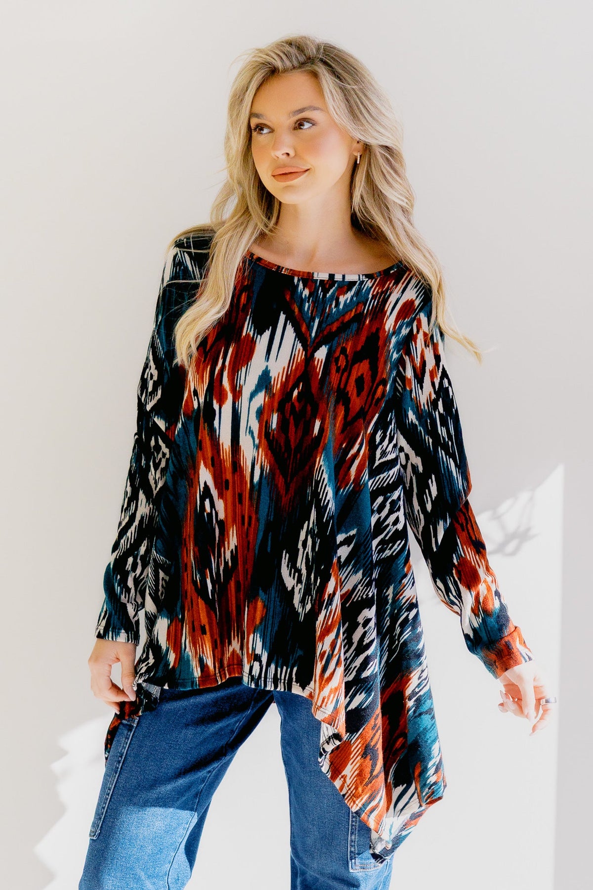 Woman wearing a multicolor tunic with a vibrant Aztec print and shark-bite hem.