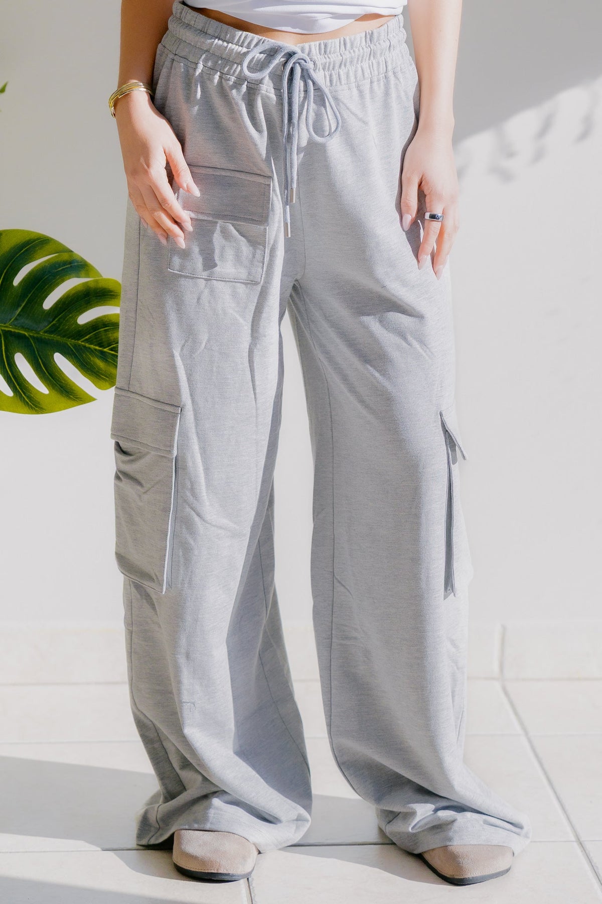 Heathered grey wide-leg cargo pants with elastic waistband and drawstring, featuring cargo pockets.