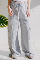 Heathered grey wide-leg cargo pants with elastic waistband and drawstring, featuring cargo pockets.