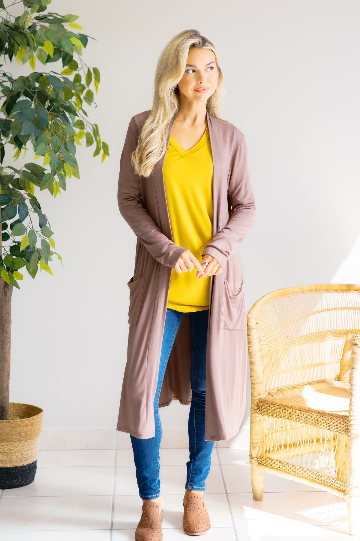Woman wearing a mocha-colored cardigan with 3/4 sleeves, over a yellow top and jeans.