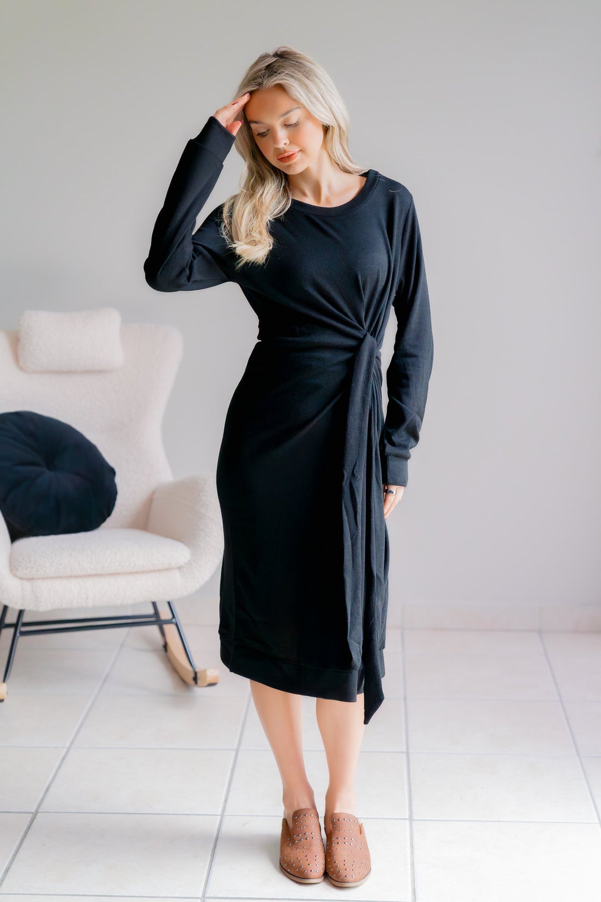Black hacci knit dress with a side tie, worn by a model standing indoors.