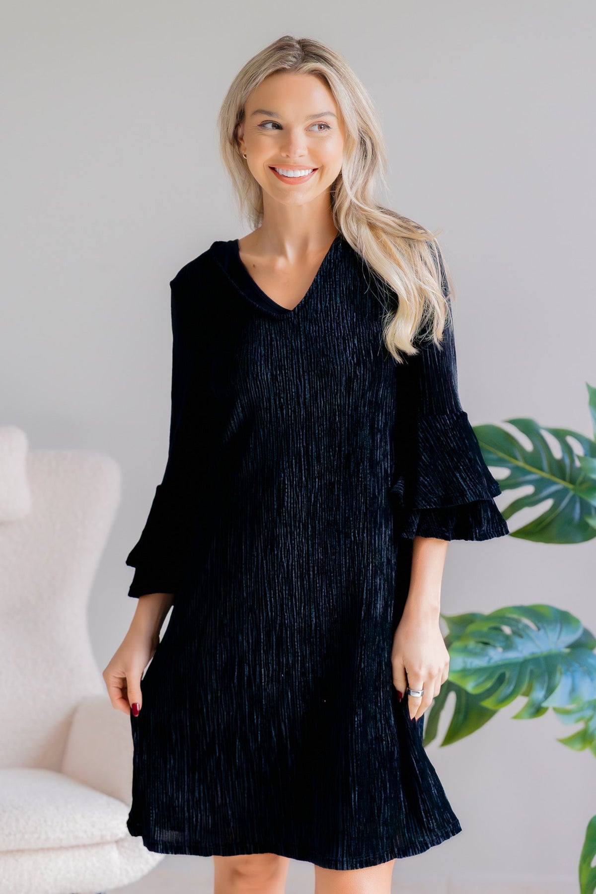 Black dress with shimmering glitter, V-neck, and 3/4 bell sleeves worn by a model.