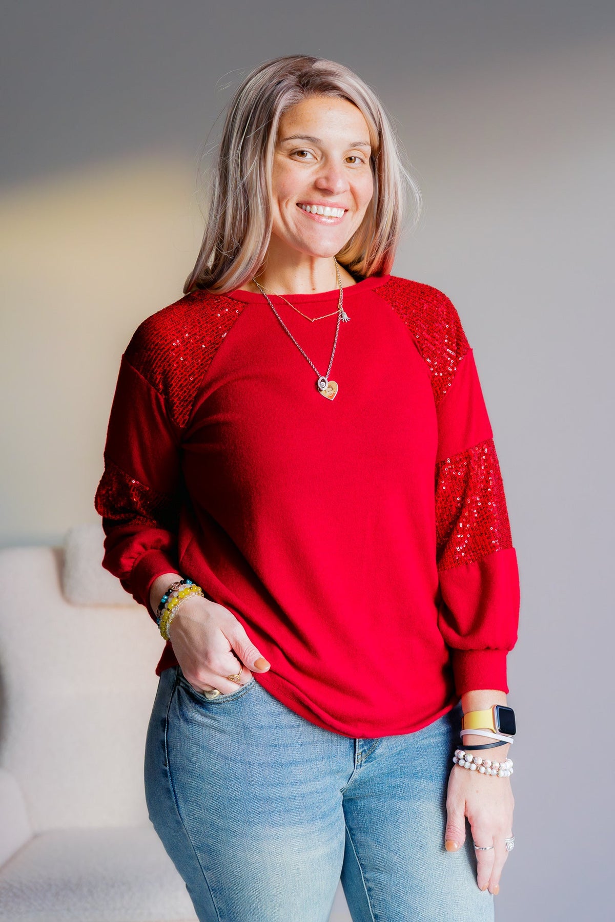 Red long sleeve knit top with sequin bishop sleeves worn by a model.
