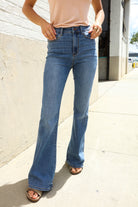 Woman wearing blue flared jeans on a sidewalk.