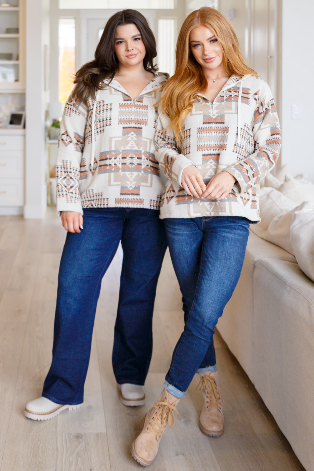 Two models wearing a beige Aztec pattern hoodie with front pockets and half-zip design.