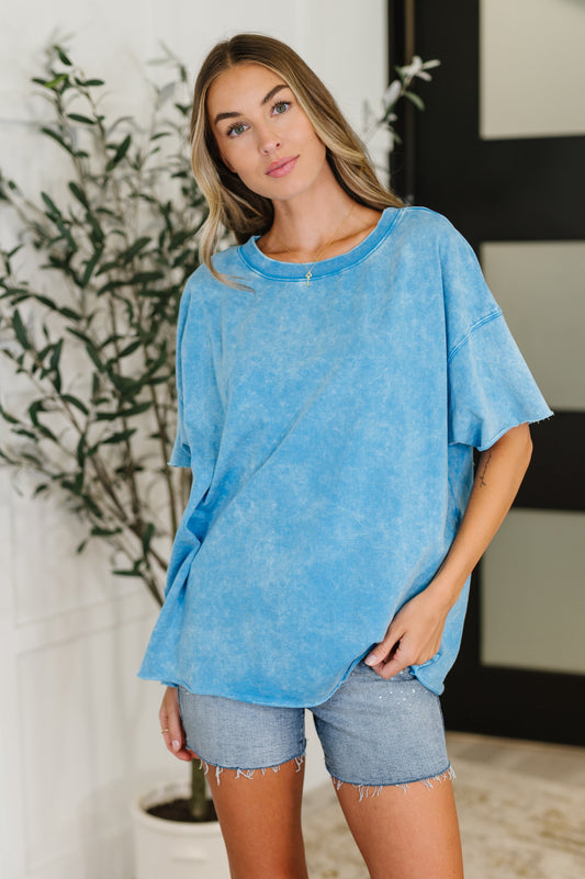 Woman wearing a blue oversized shirt and denim shorts indoors.