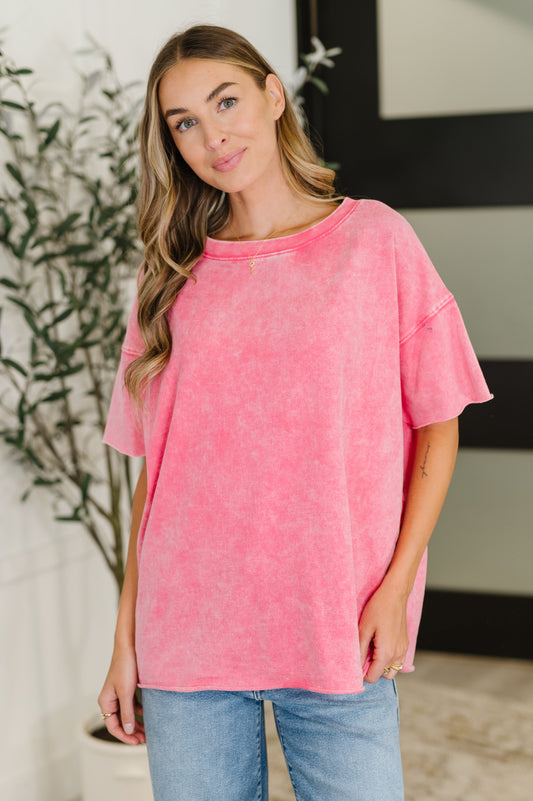 Woman wearing a pink oversized t-shirt and blue jeans indoors.