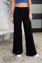 Black high-waist palazzo jeans with a wide-leg fit and zip fly closure.