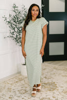 Woman wearing a green and white striped dress standing indoors.