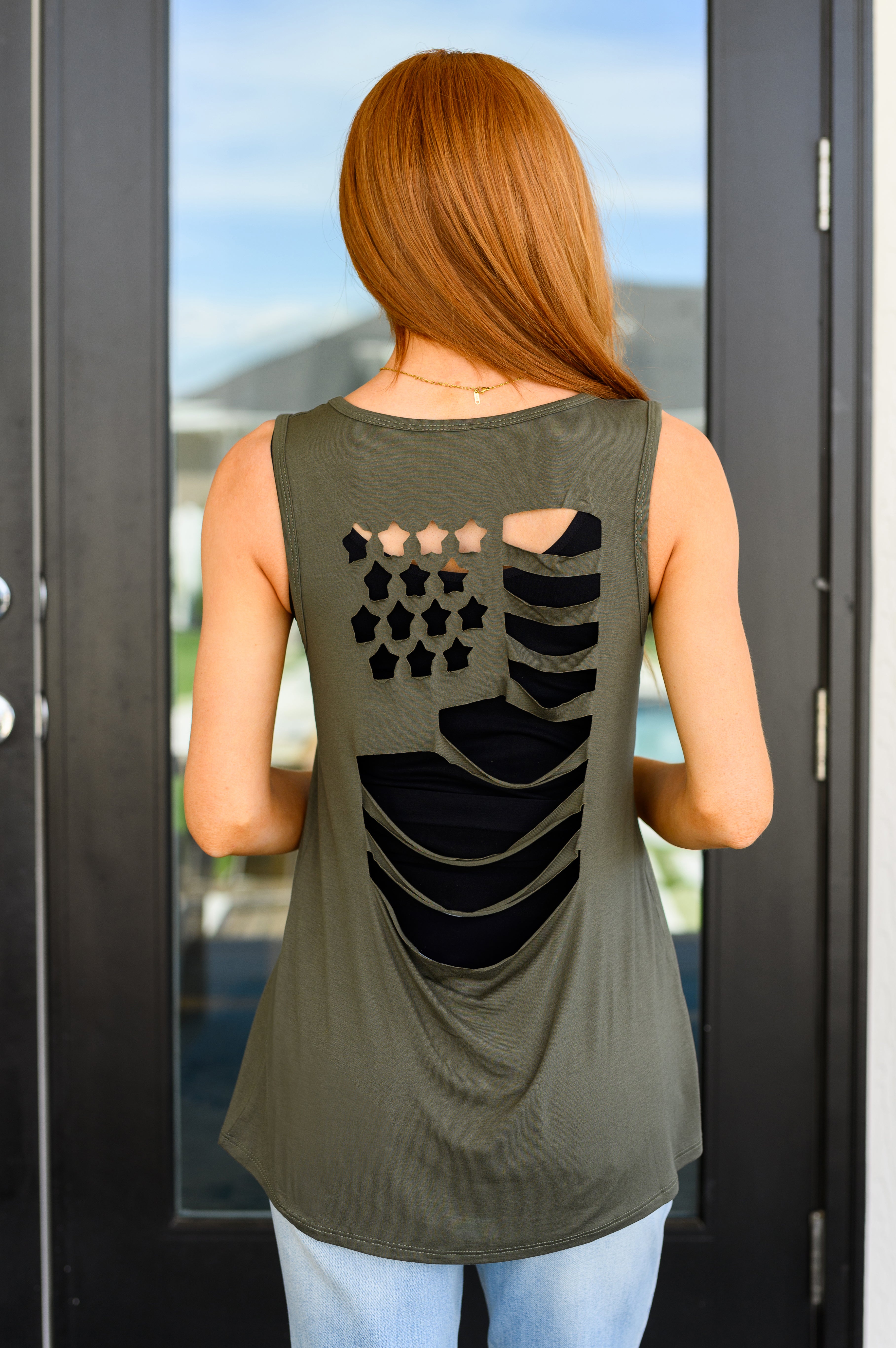 A woman wearing olive green tank top with a v-neckline and a cut-out flag design on the back