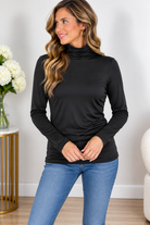 A woman wearing a black turtleneck top with long sleeves and a soft, stretchy fit.