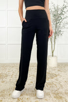 A woman wearing straight leg black Activewear bottoms with a banded waistband and patch pockets.