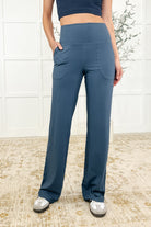 A woman wearing straight leg blue Activewear bottoms with a banded waistband and patch pockets.