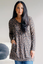 Woman wearing a leopard print V-neck tunic in oatmeal with long sleeves.