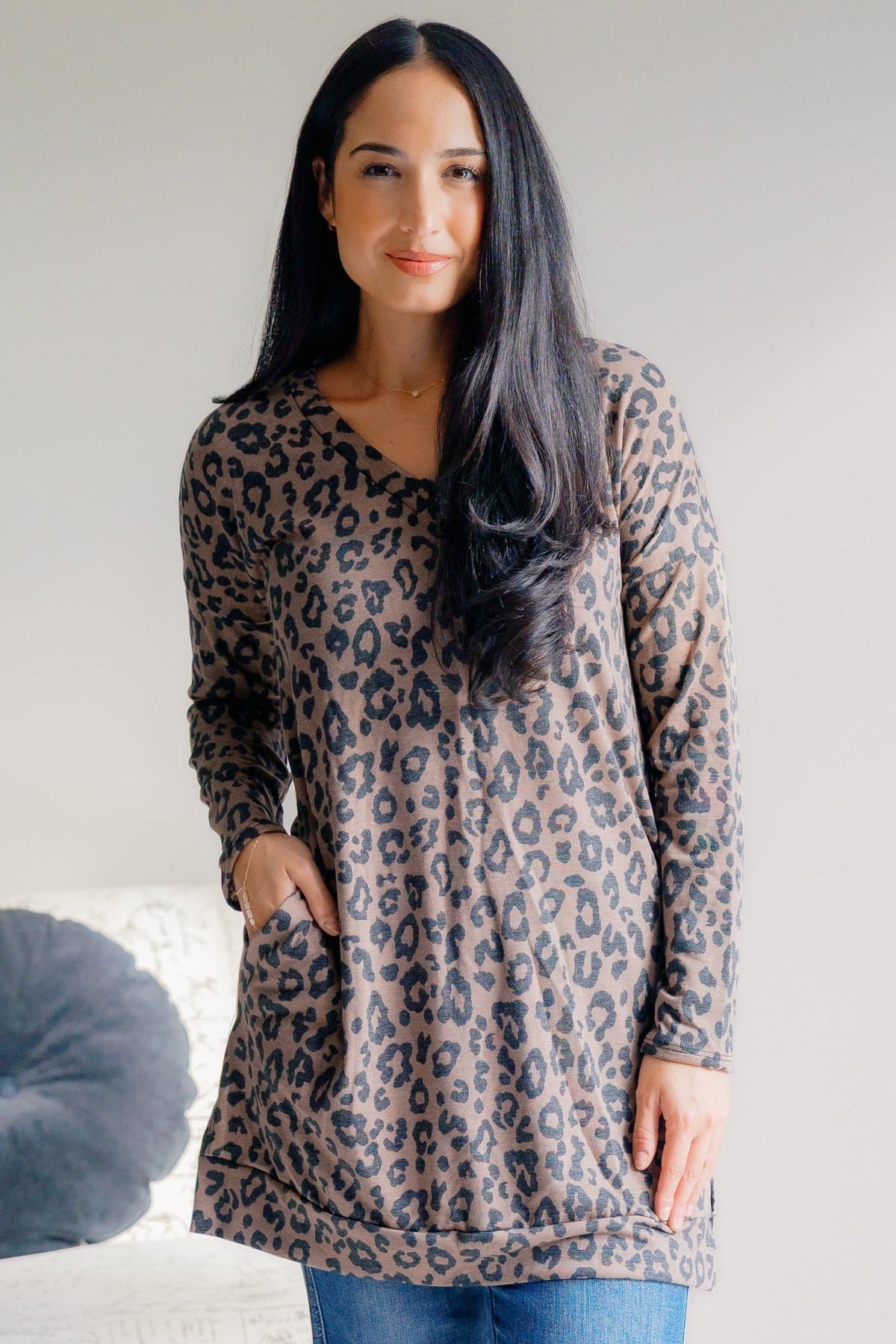 Woman wearing a leopard print V-neck tunic in oatmeal with long sleeves.