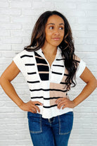 A woman wearing a striped quarter zip vest in white, with the vest showcasing a relaxed fit and banded sleeve cuffs.