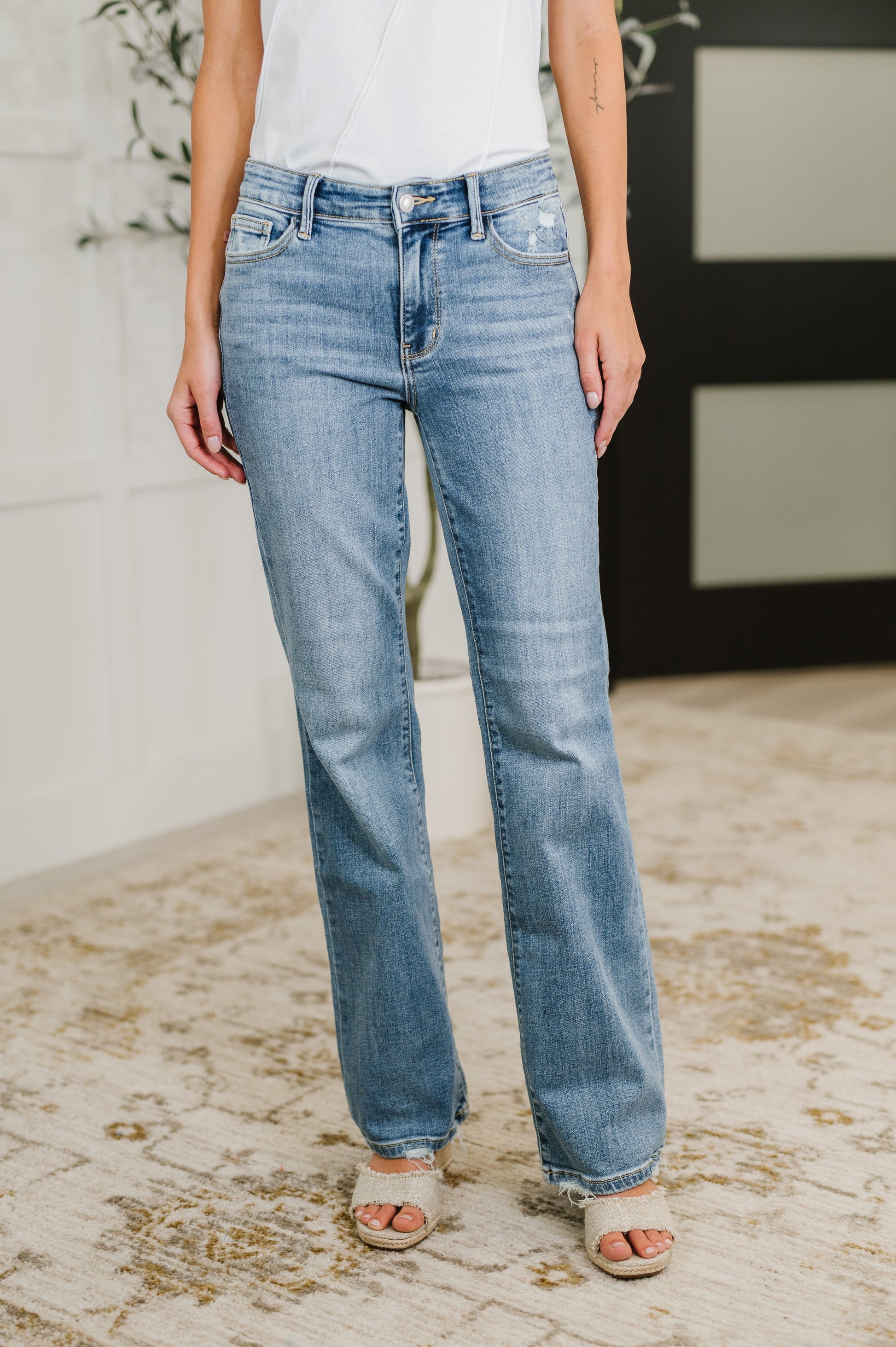 Woman wearing light blue jeans on a textured floor.