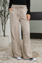 Woman wearing beige wide-leg pants with a neutral background
