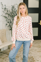 Model wearing a long sleeve top with red hearts, banded ribbed cuffs, and hemline.