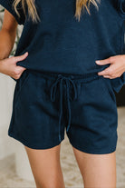 Navy blue textured outfit with shorts and top on a blurred background