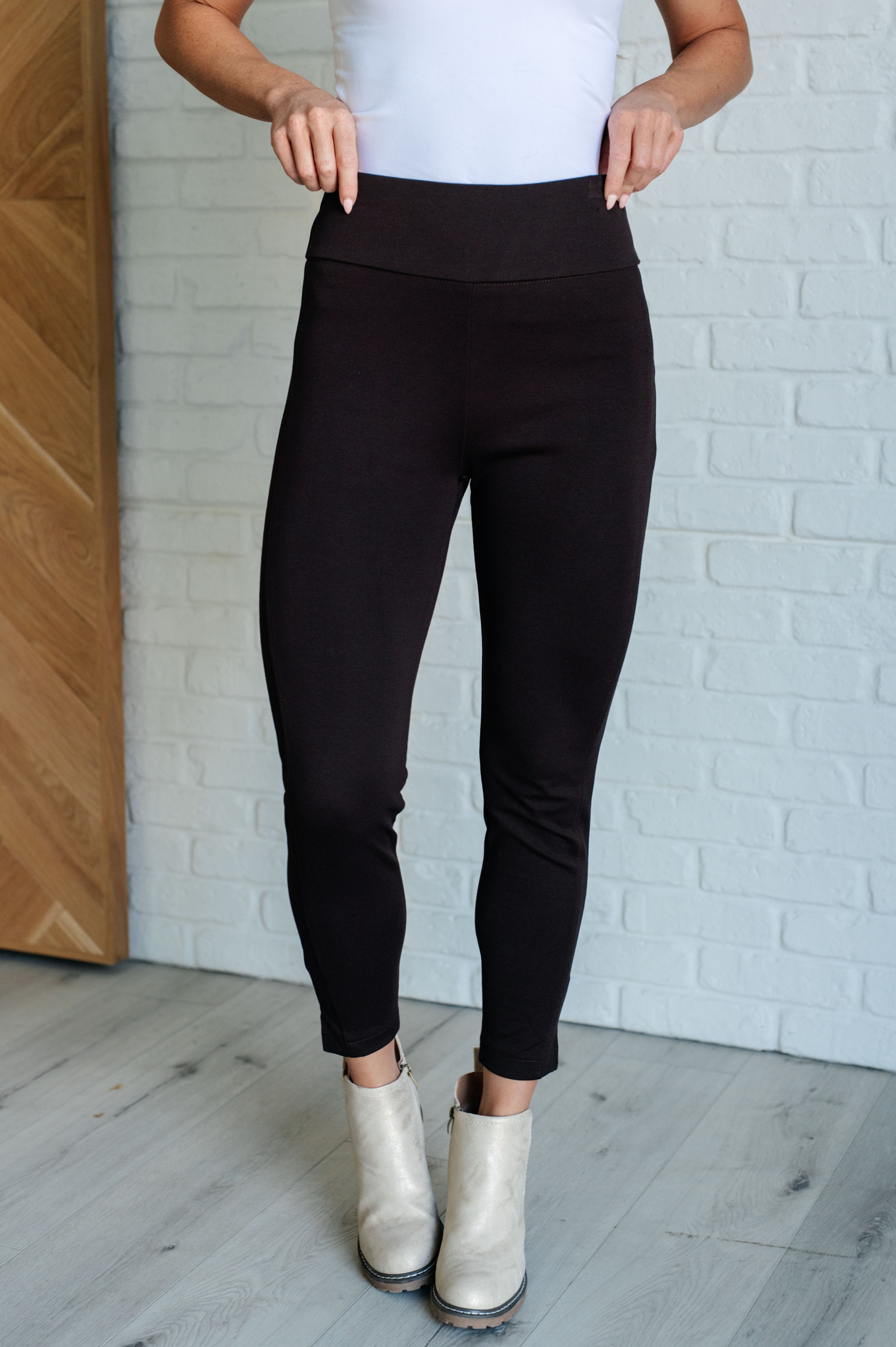 A pair of high-waisted, slim-fit chocolate-colored Magic Skinny Pants with faux welt pockets, paired with a white cropped top.