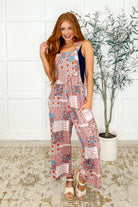 Woman wearing straight leg overalls with a geometric pattern, featuring a square neckline and adjustable straps.
