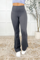 Woman wearing gray flared yoga pants with a high waisted design and banded waist.