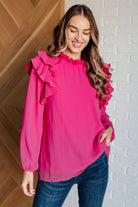 A woman wearing a pink top with ruffles and balloon sleeves, styled with jeans.
