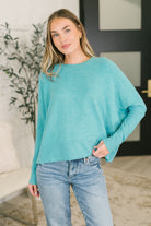 Aqua dolman sleeve top with ribbed cuffs and hem, worn by a model with jeans.